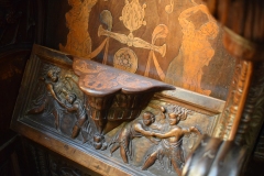 When the clergy were supposed to stand but wanted to lean, they could flip up their seats and half-sit in a mostly standing position using this very decorated protrusion.