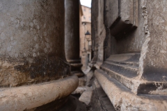 Behind the pillars at the top of the stair.